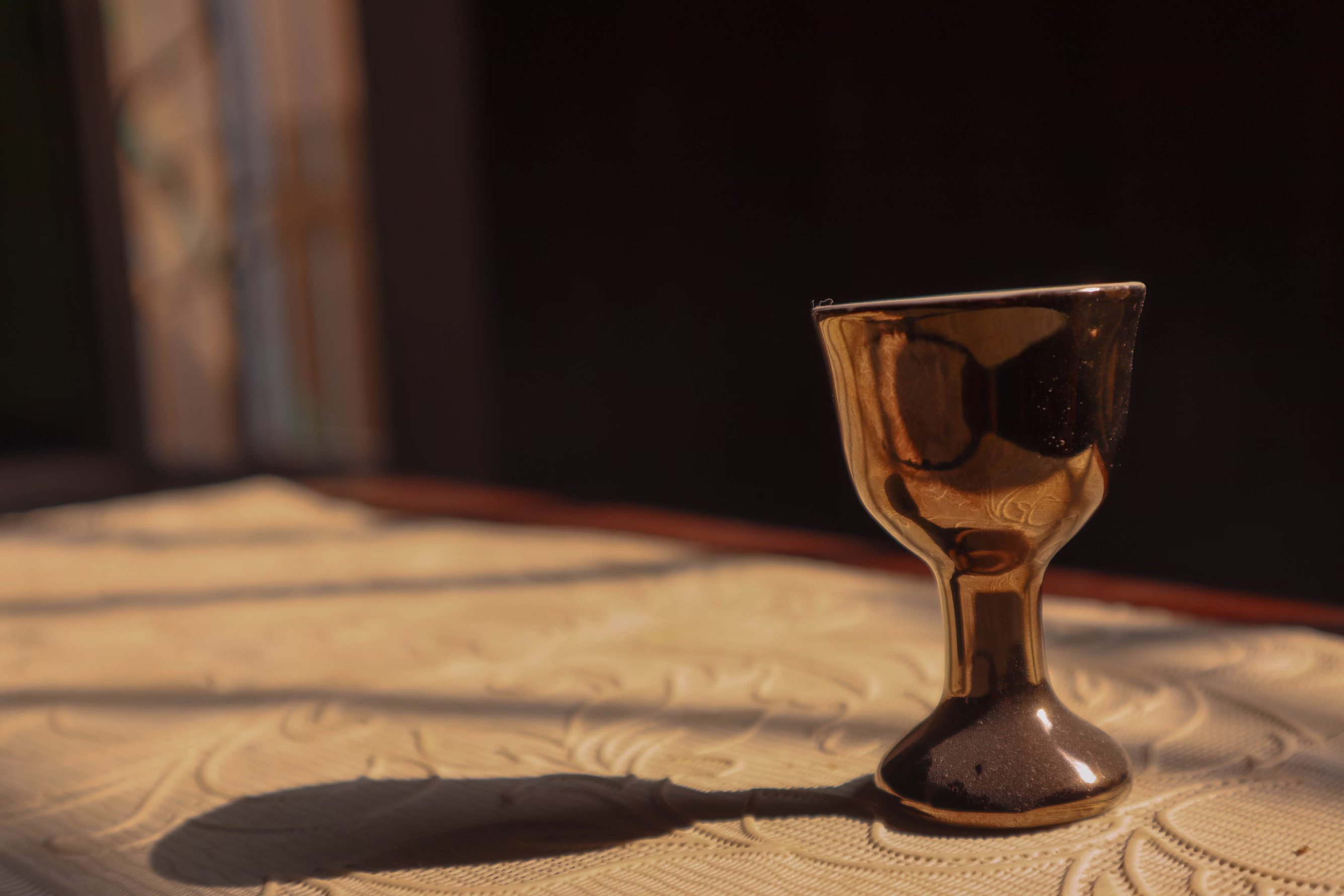 A humble copper cup sitting in warm light, casting a long shadow